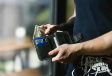photograph of person holding black leather wallet with money Kenya faces economic strain with layoffs and cash flow issues; resilience, skill-building, cost optimization, and government support are key to recovery.